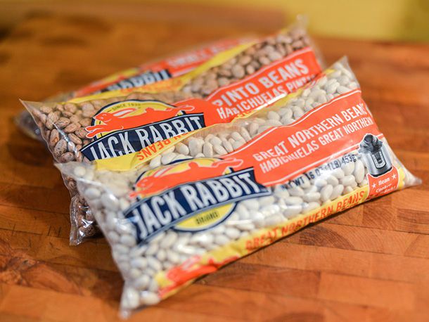 Three bags of dried beans: pinto beans, great northern beans, and small red beans.