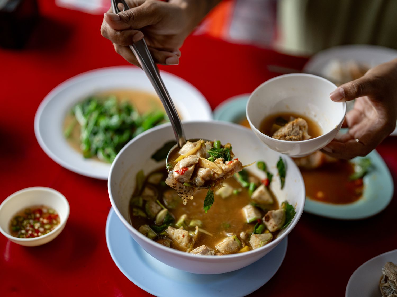 Spooning thai soup into a bowl