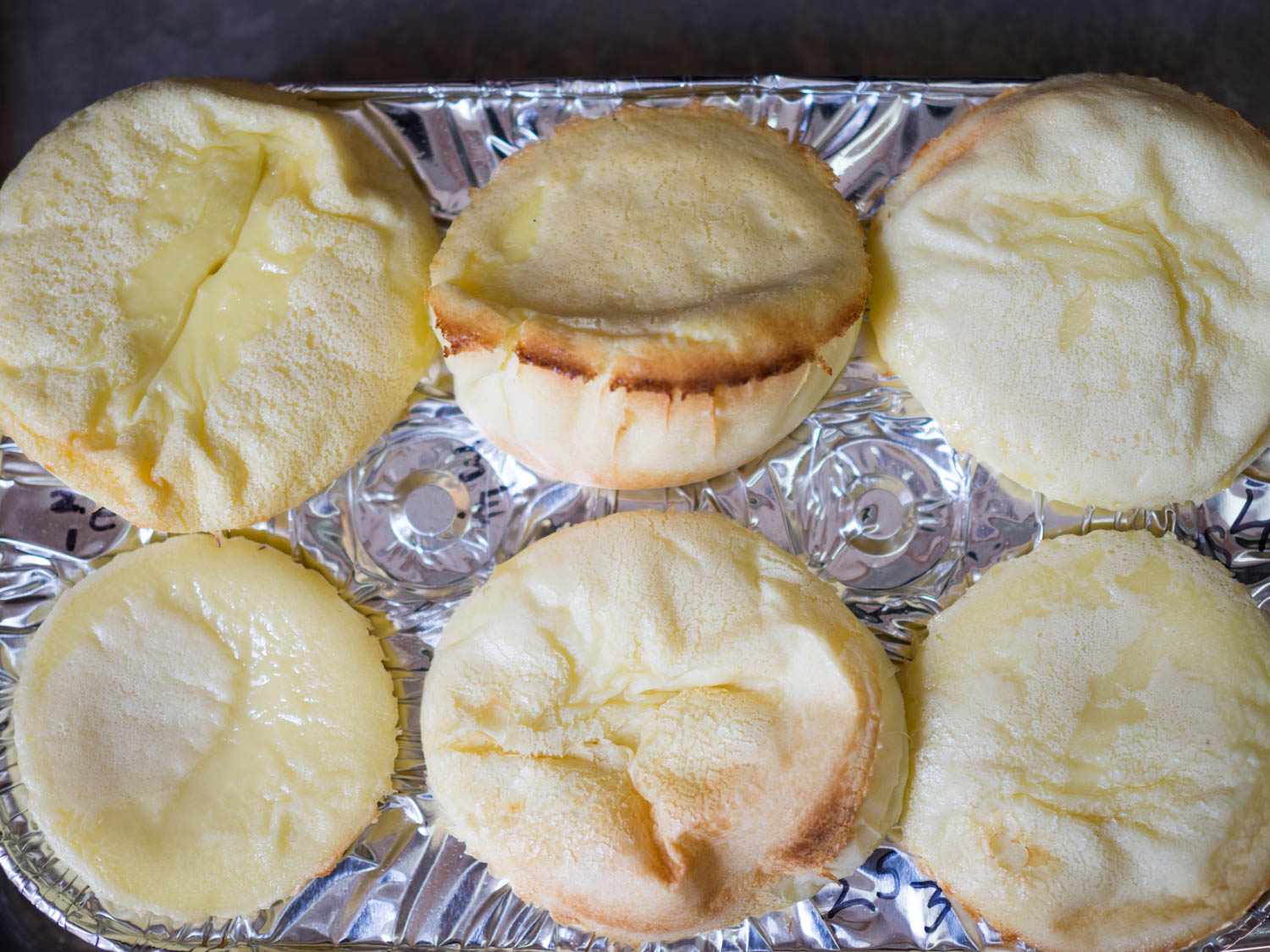 Testing egg and sugar amounts for clafoutis batter in a six-cup muffin tin, clockwise from bottom left: 1 egg per cup of milk; 2 eggs per cup of milk; 3 eggs per cup of milk; 4 tablespoons sugar per cup of milk; 3 tablespoons sugar per cup of milk; 2 tablespoons sugar per cup of milk.