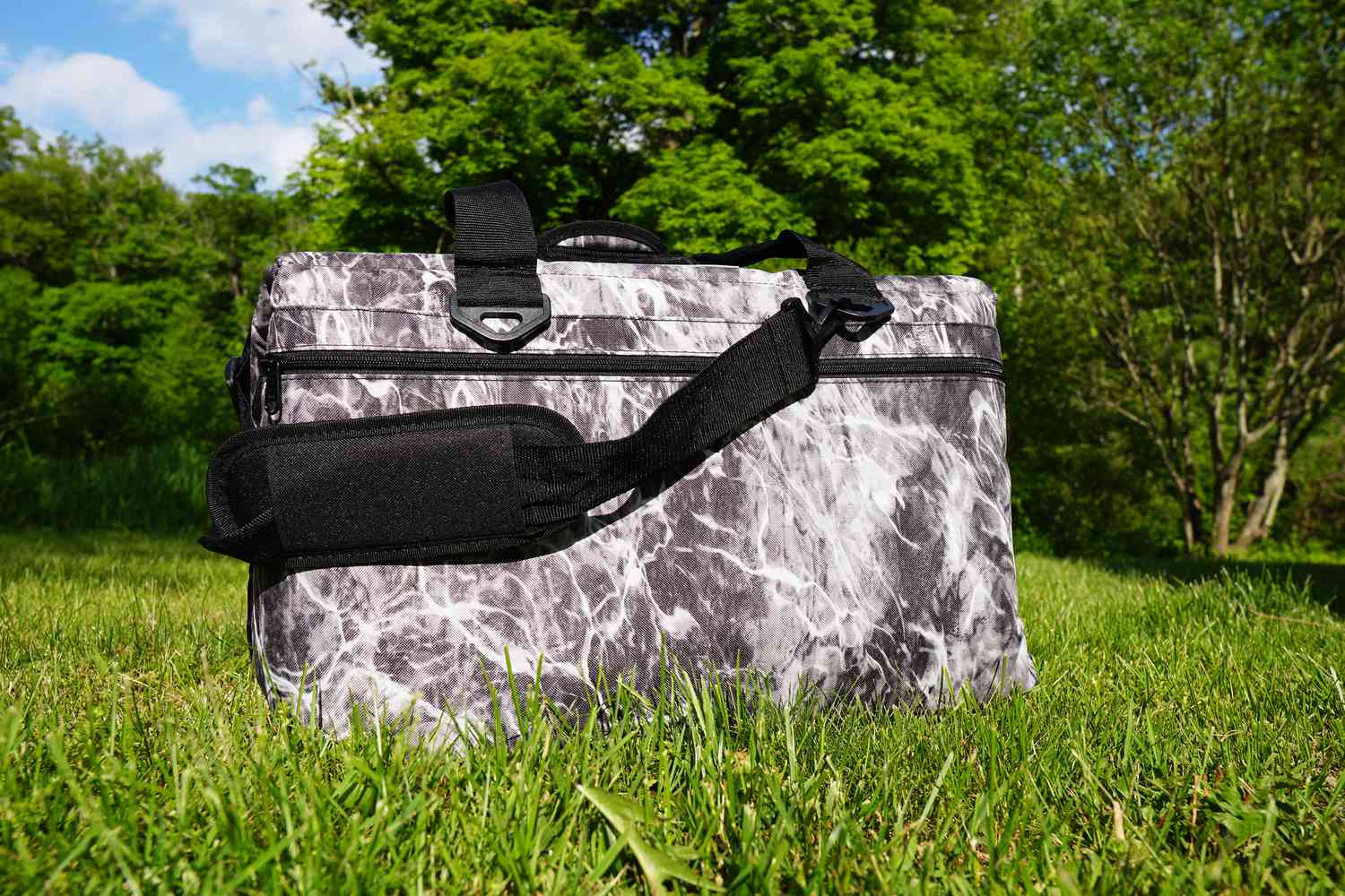 a grey and white soft cooler on a grassy surface