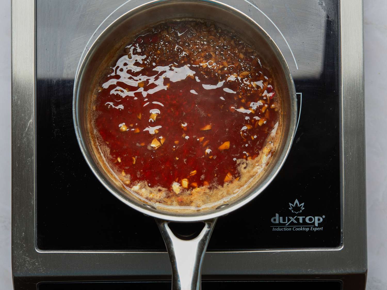Pot with simmering tamarind marinade placed on an induction cooktop