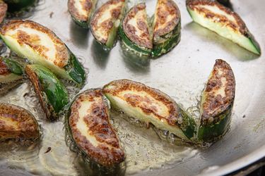 Pieces of cucumber browning in a frying pan