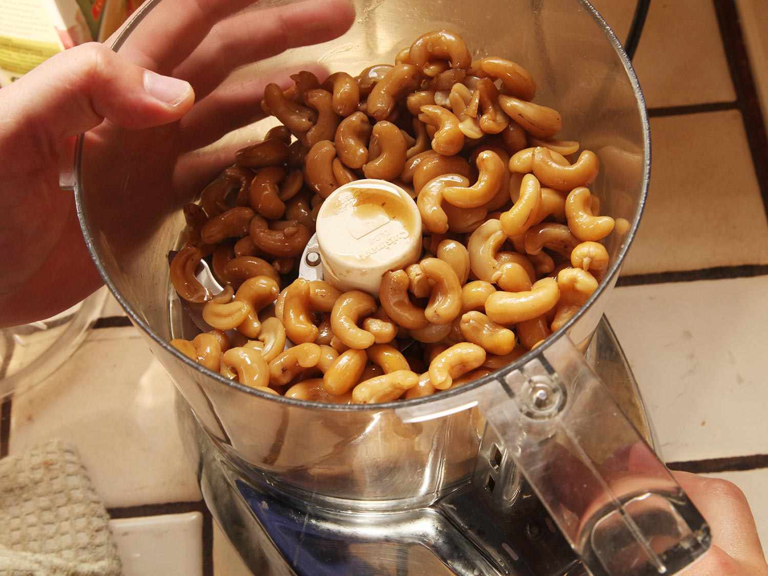 Cooked cashews in the bowl of food processor.