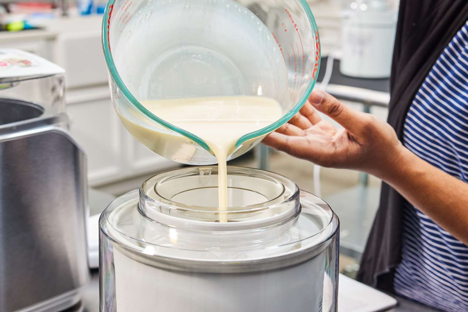  Hands pouring ice cream base into an ice cream maker