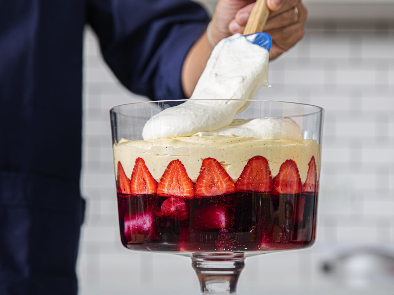 Spooning whipped cream over creme patisserie in trifle 