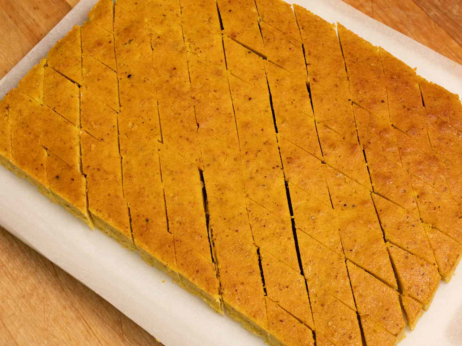 baked baklava cake cut into squares on parchment paper on a wooden surface 