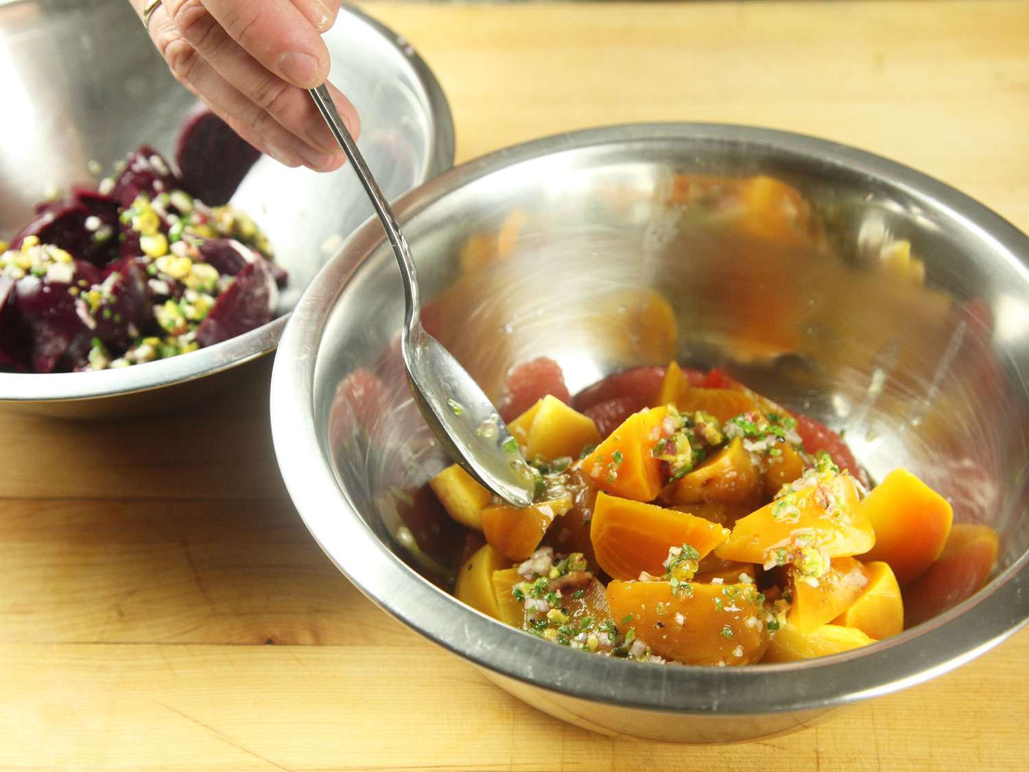 Drizzling pistachio vinaigrette over a beet and citrus salad, but keeping different colored beets in separate bowls while tossing.