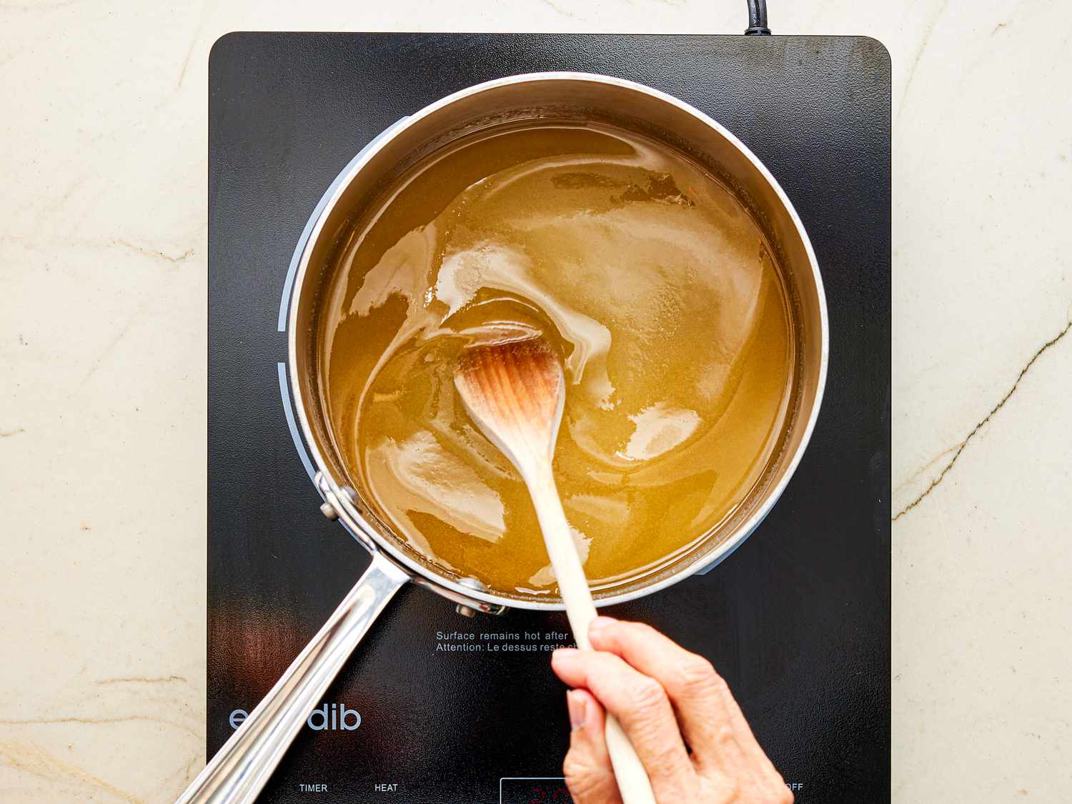 Overhead view of stirring honey mixture in pot