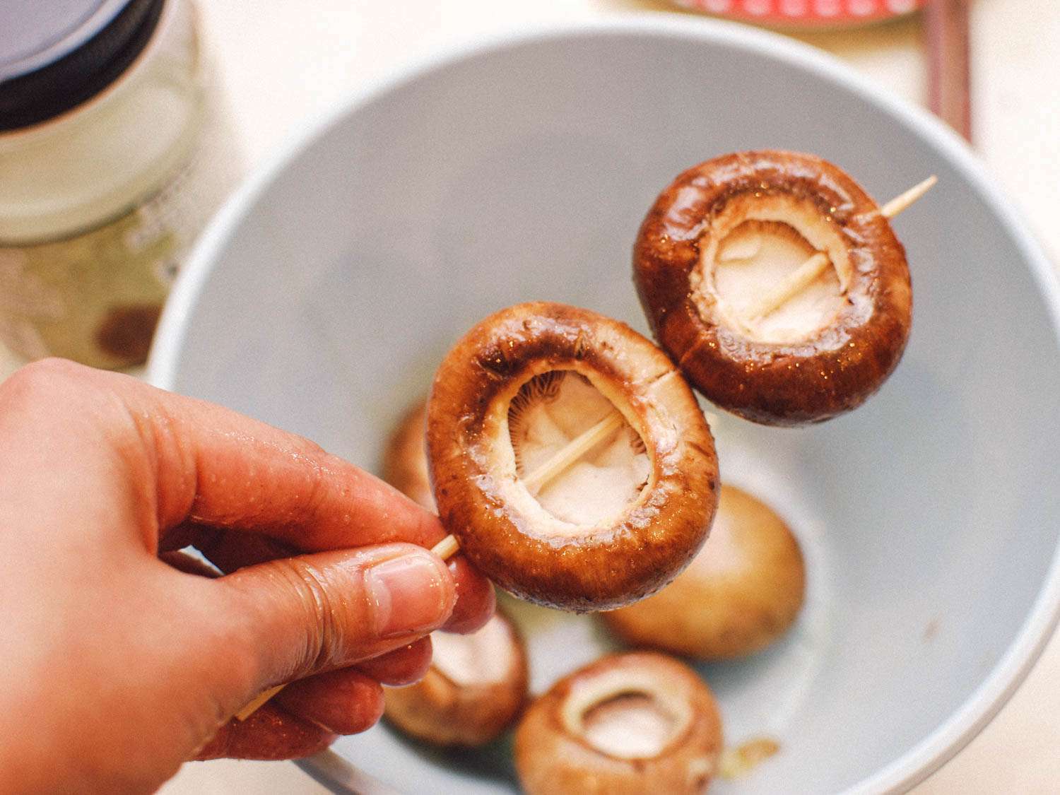 Skewering cremini mushrooms to prepare for grilling.