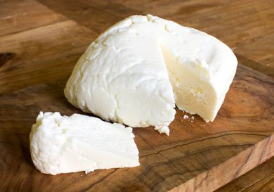 A cut of queso fresco resting on a cutting board