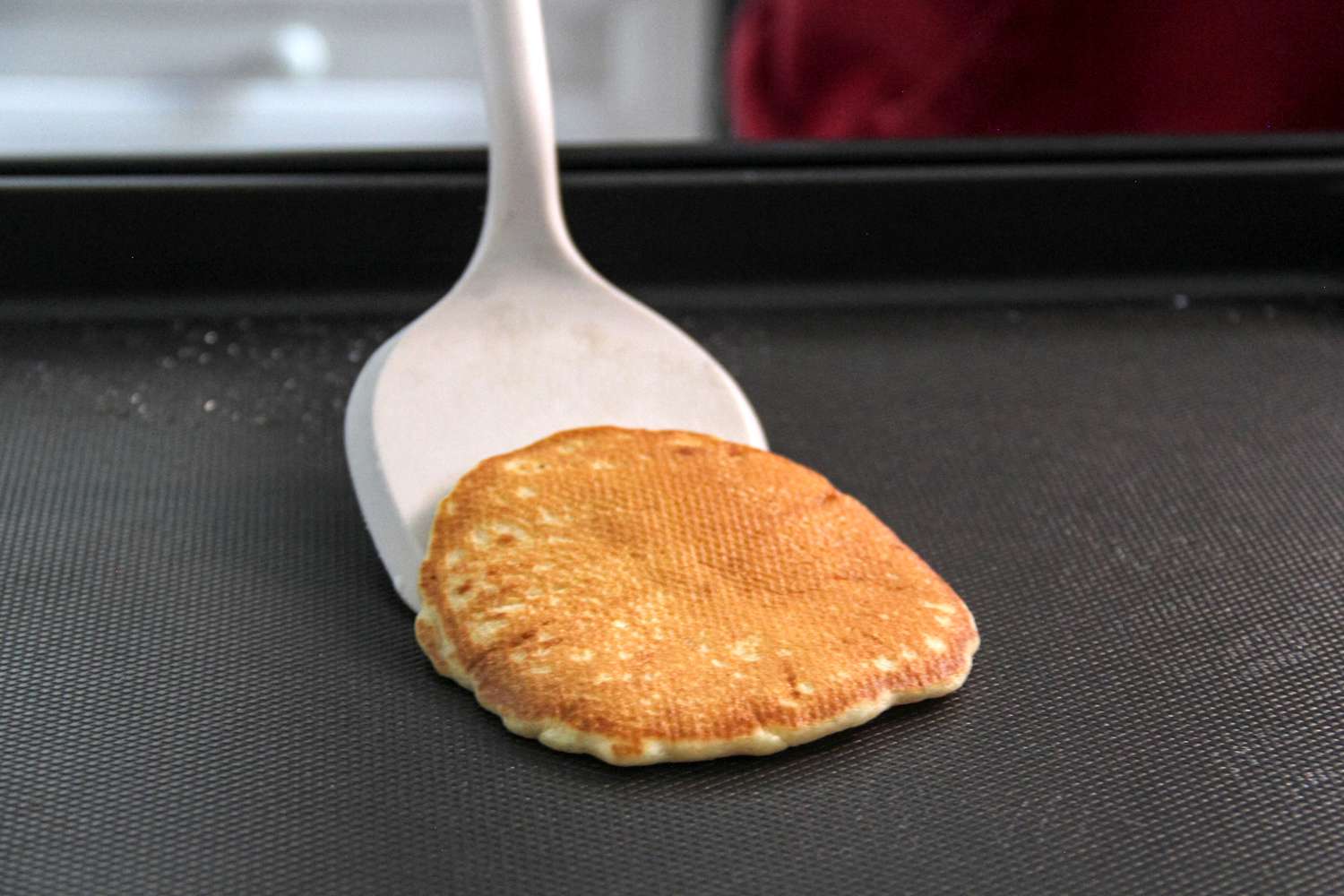 A person using the Material Soft-Edged Turner to flip food