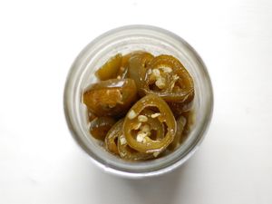 Overhead view of cnadied jalapeños in a half-pint jar.