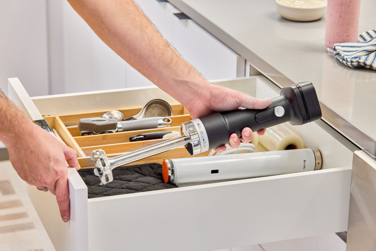 A person places the KitchenAid Go Cordless Hand Blender into a drawer