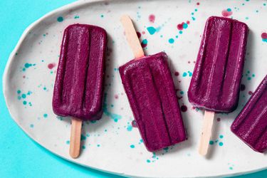 Blueberry yogurt popsicles arranged on a speckled platter