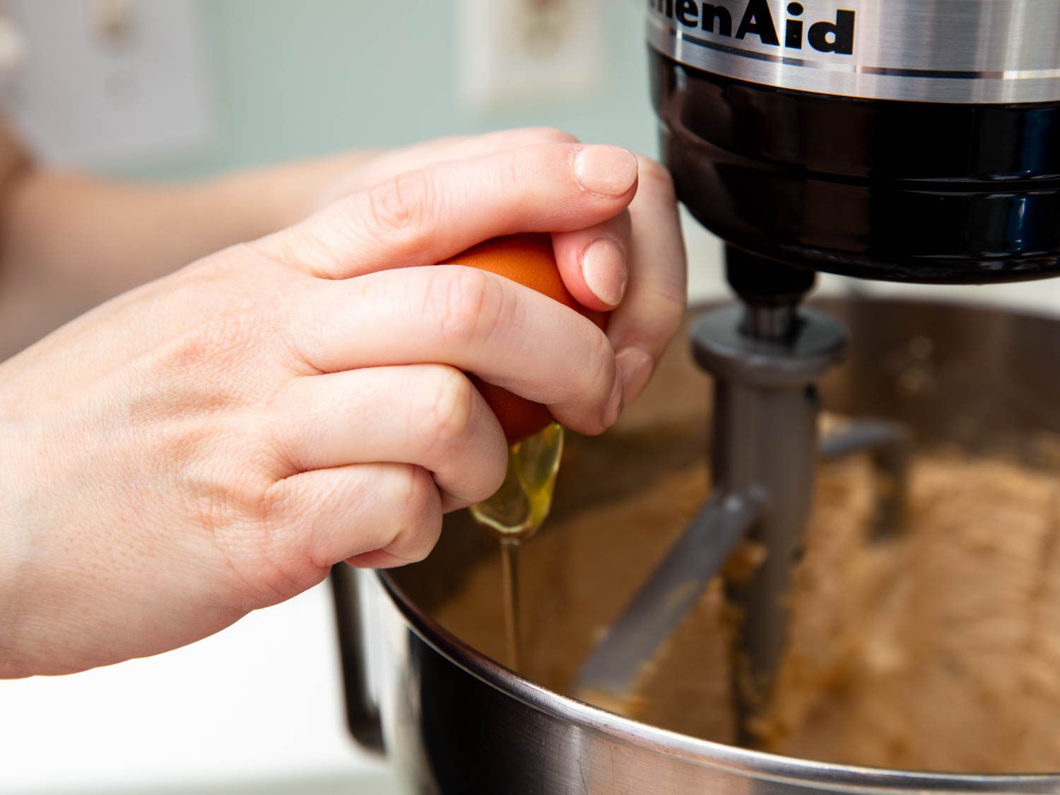 Cracking an egg into a stand mixer bowl while the motor is running.