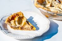 A slice of pie on a decorative white plate placed next to a OXO Good Grips Glass Pie Plate with the remaining pie