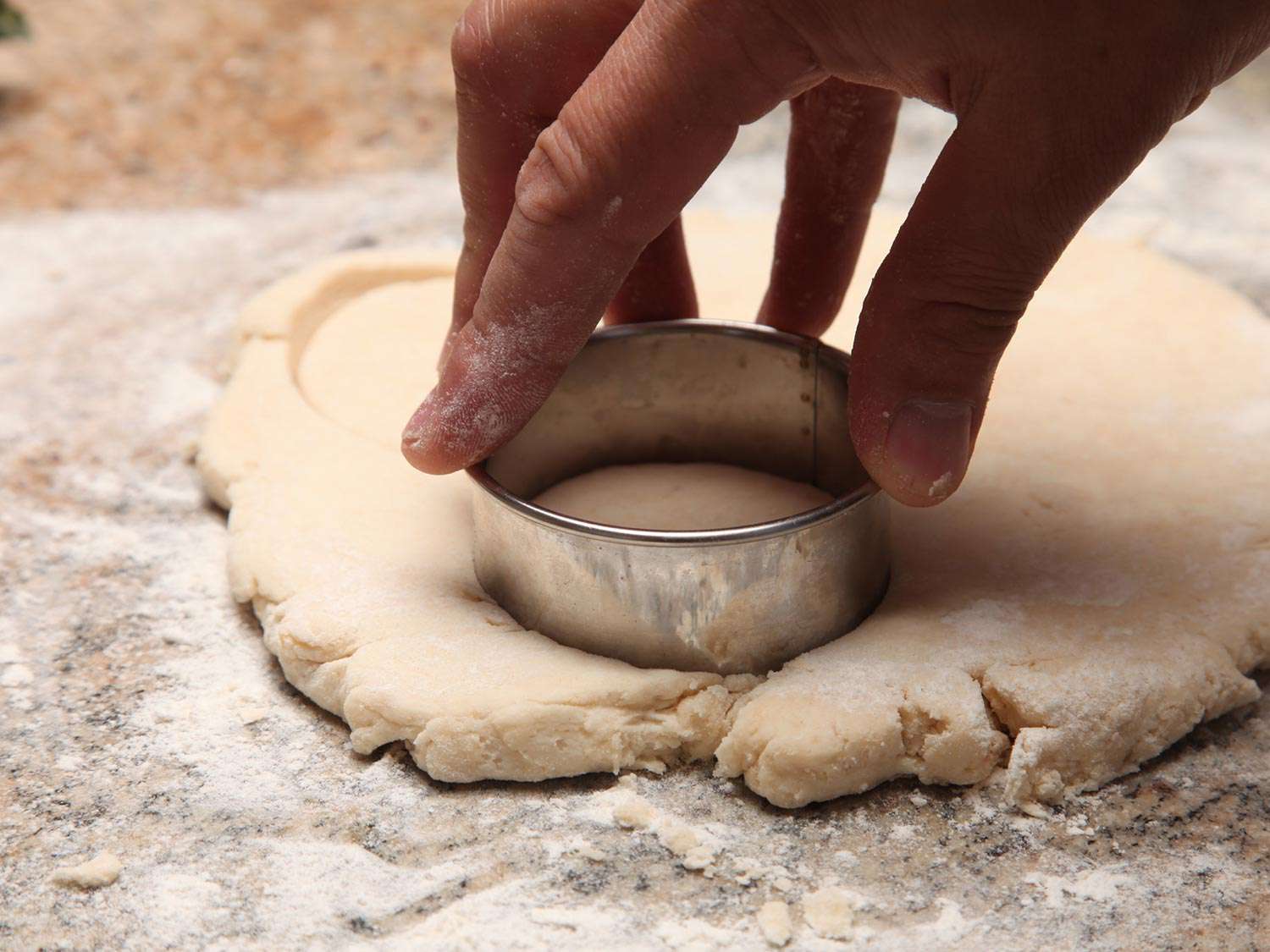 Using a round biscuit cutter to cut two-ingredient biscuits out of dough.