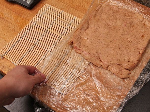 Transferring plastic-wrapped foie gras to sushi mat. 