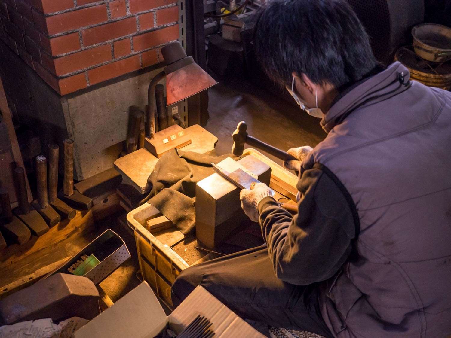 A Japanese bladesmith pounding a nearly-finished knife by hand.