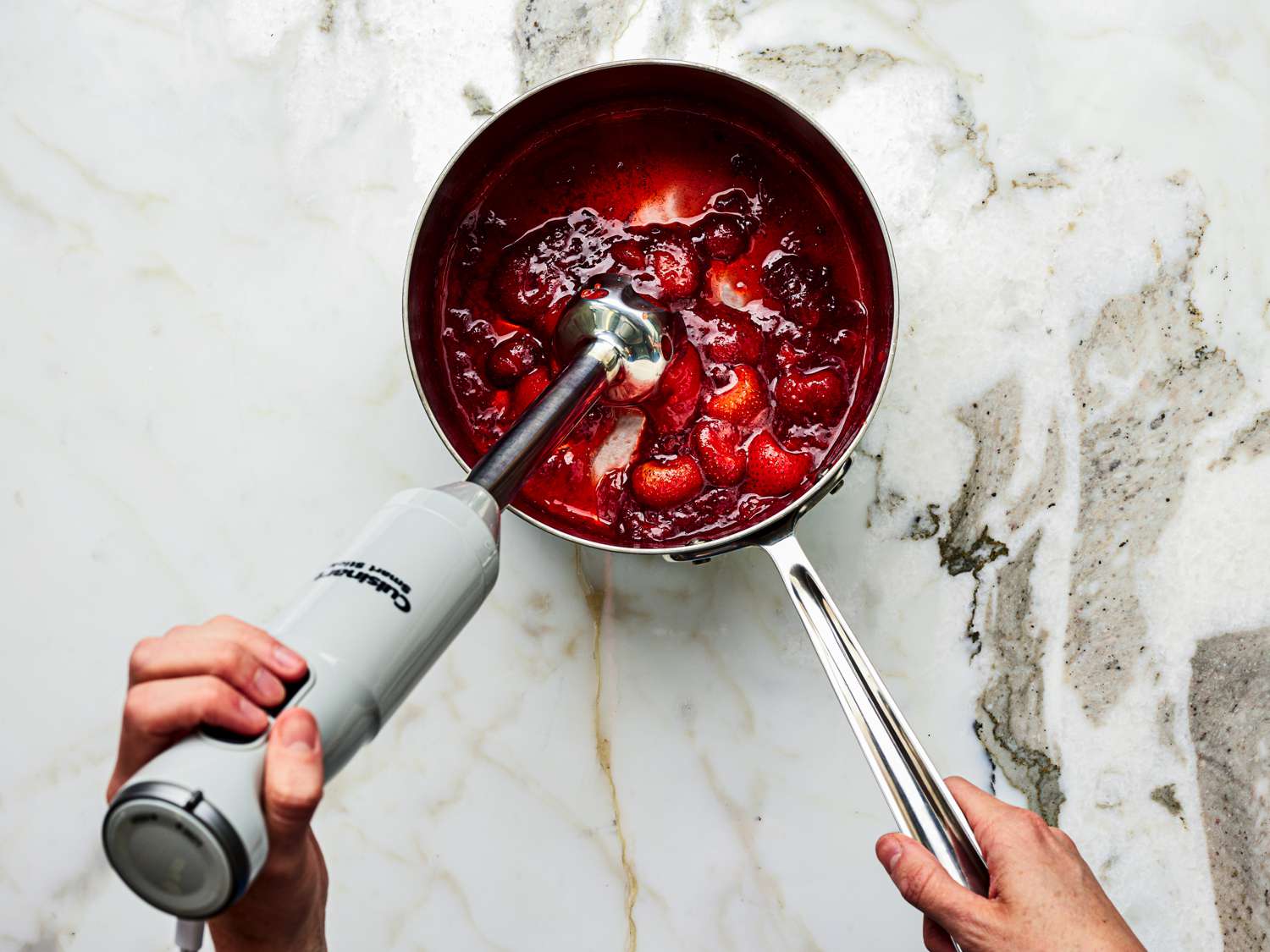 Overhead view of using an immersion blender on the sauce