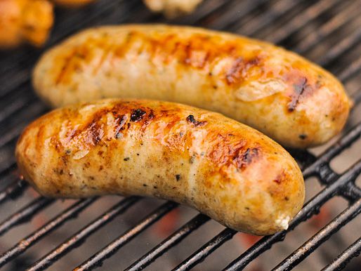 Closeup of garlic feta chicken sausages browning on a grill grate.
