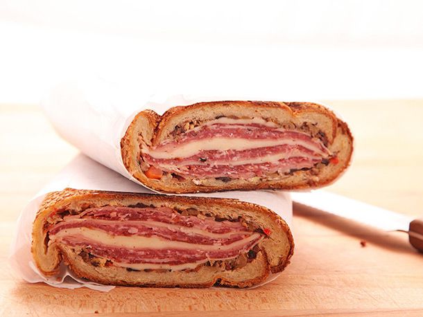 cross-section of two halves of pressed muffaletta wrapped in paper