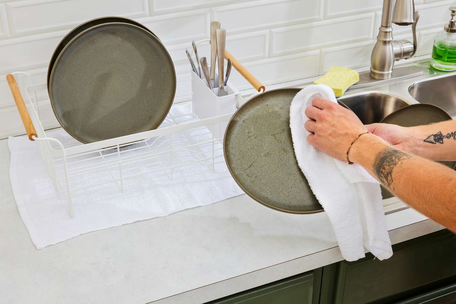A person using a white bar mop to dry a plate.