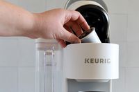Person operating the Keurig K-Supreme Single Serve K-Cup Pod Coffee Maker