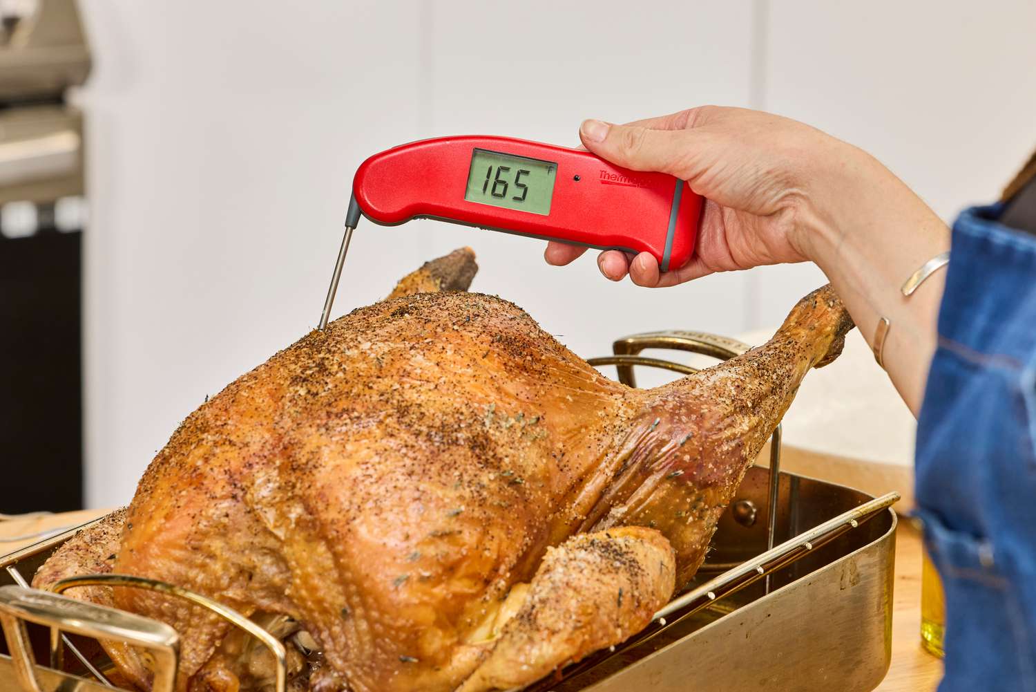 A person poking a meat thermometer into the breast of a fully-cooked KellyBronze Turkey
