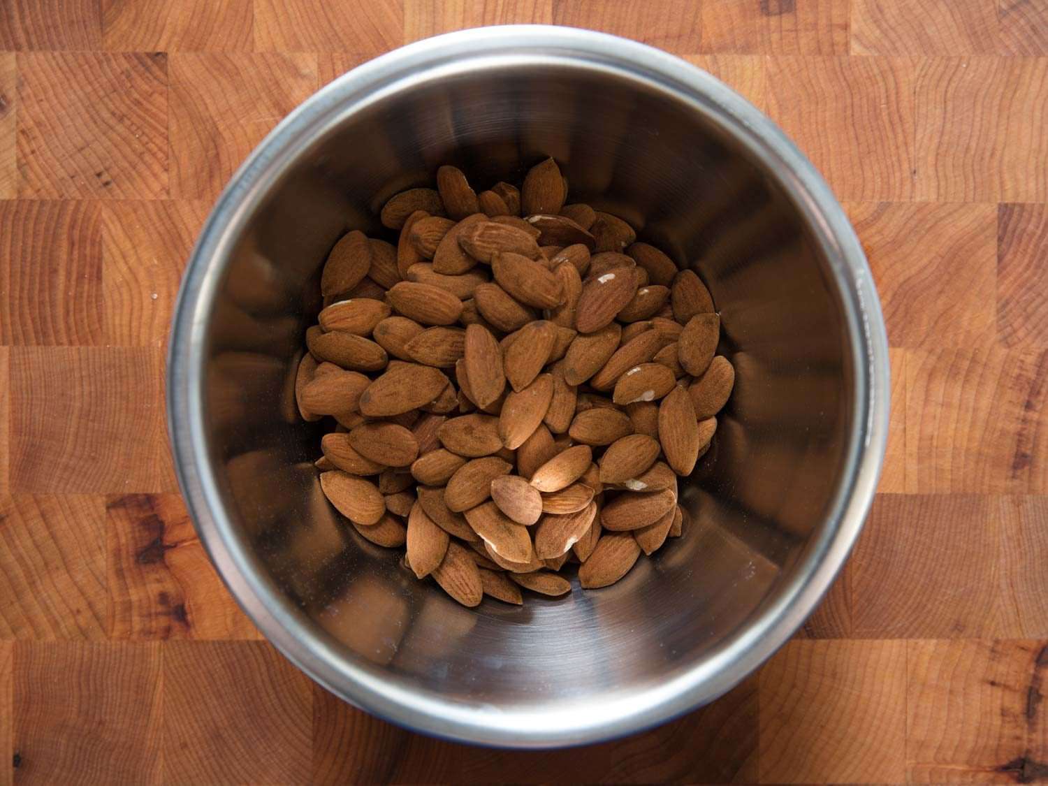Overhead shot of raw almonds in a metal bowl.