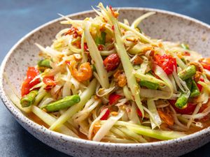 Side view of som tum thai (green papaya salad) in a serving bowl.