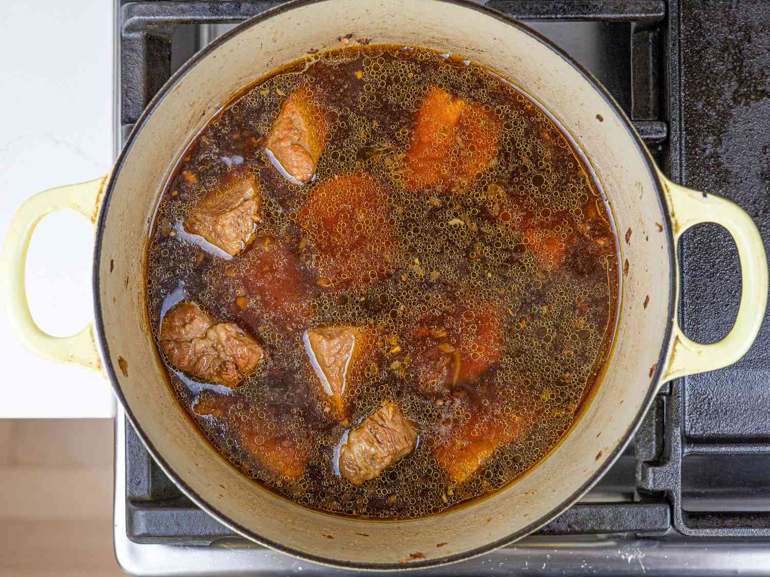 Pork submerged in vegetable stock in a Dutch oven