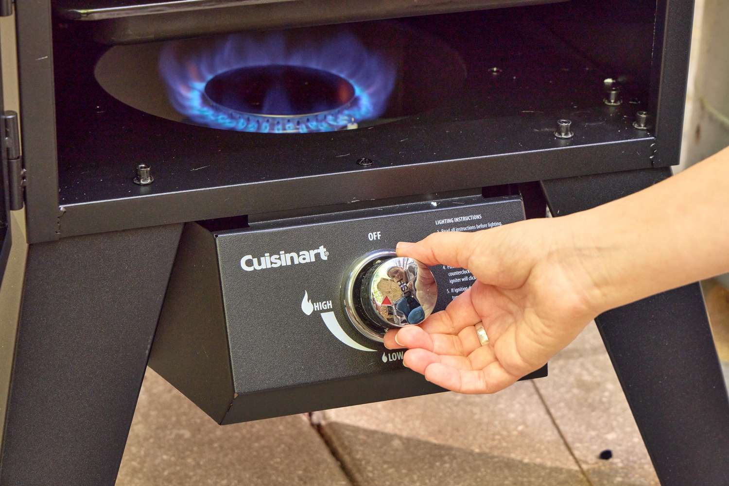 A person turns a dial on the Cuisinart COS-244 Vertical 36-inch Propane Smoker