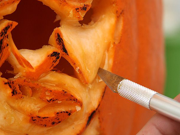 Using an X-ACTO knife to work shading into the design of a face on a pumpkin