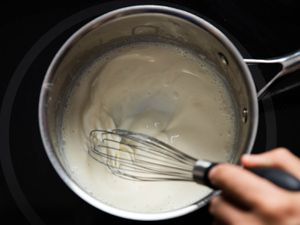 Whisking a homemade mornay sauce in a pan