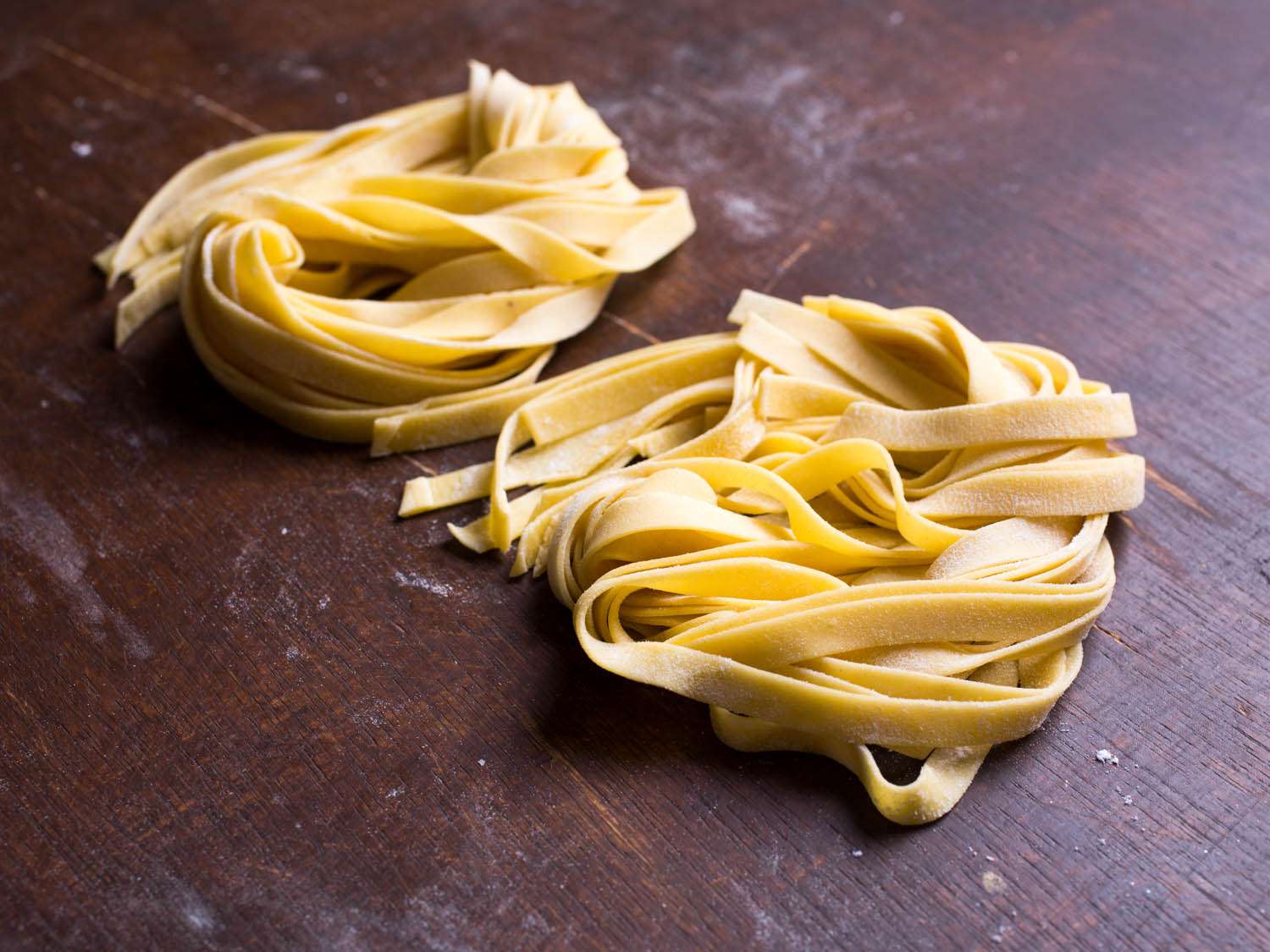 Nests of fresh pasta ribbons on a wooden surface.