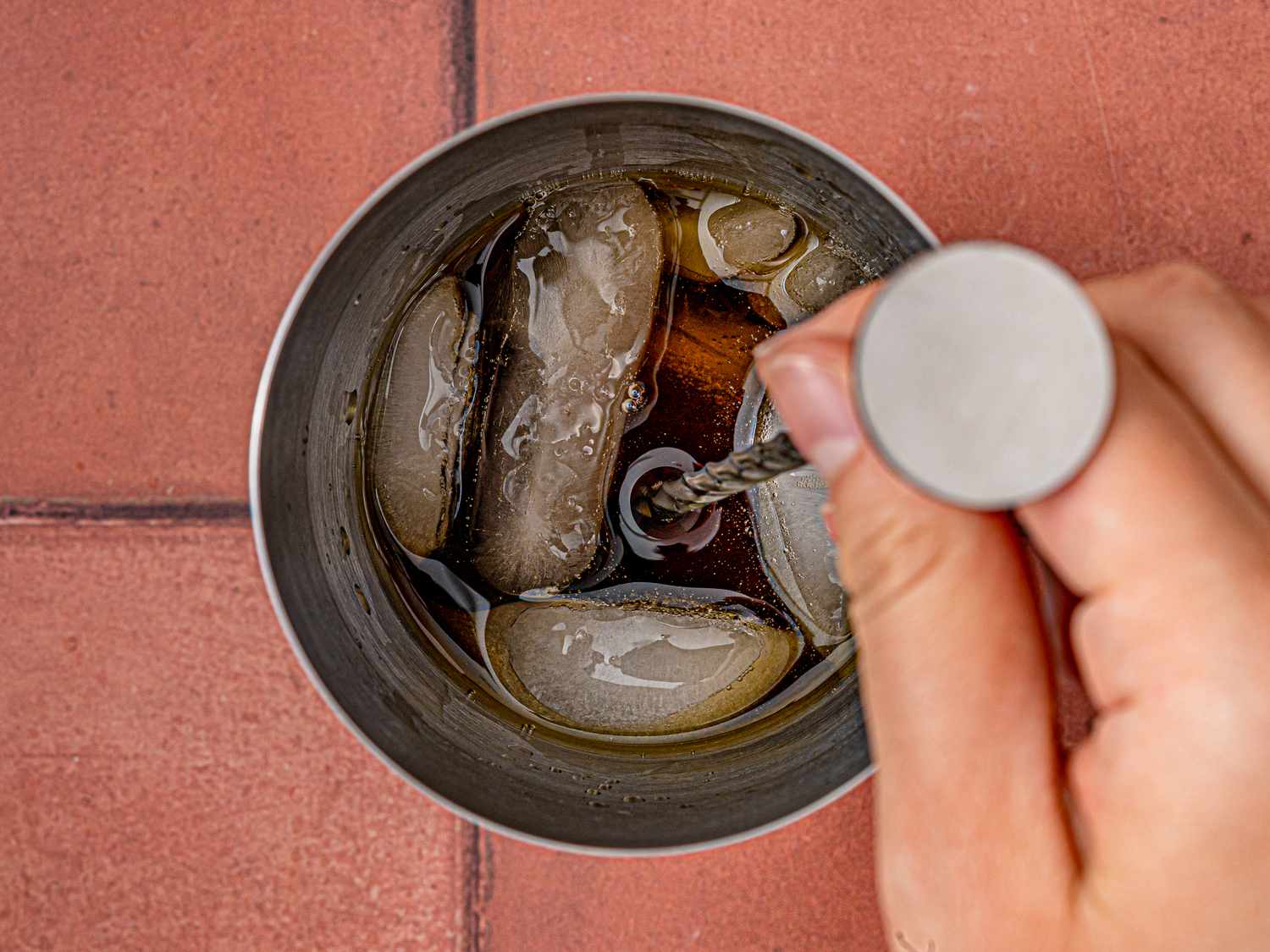 Hand stirring Manhattan in a metal shaker with ice