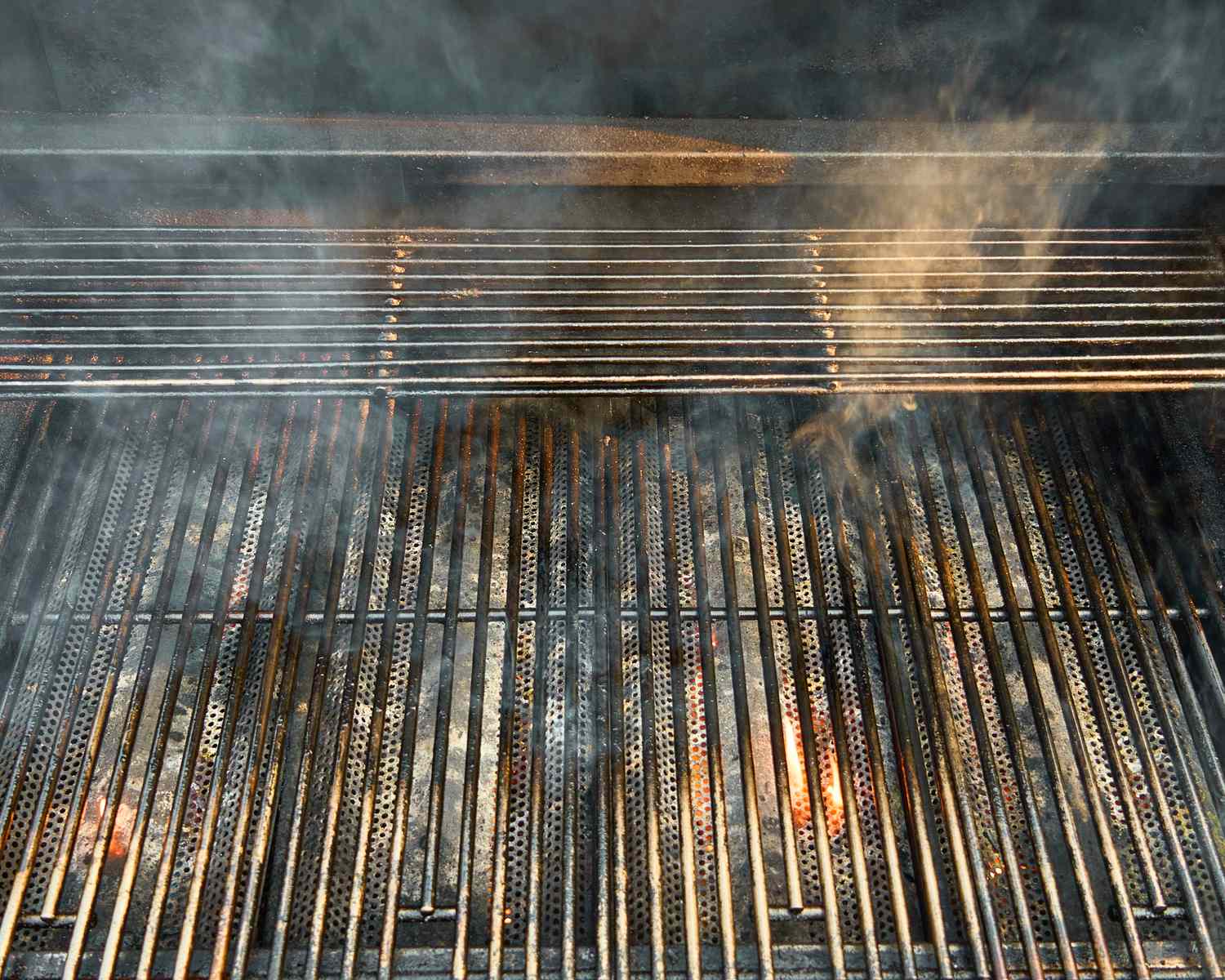 Grill grates with smoke rising preparing for cooking