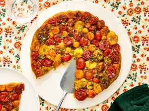 A tomato tart Tatin on a platter garnished with herbs