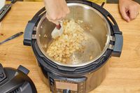 A person cooks onions inside the Instant Pot Pro 10-in-1 6-Quart Pressure Cooker