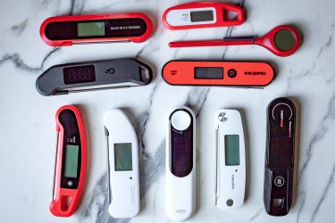 A number of instant-read thermometers on a marble countertop.