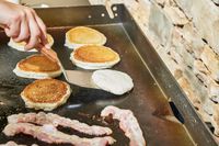 A person cooks pancakes on the Blackstone 1554 Cooking 4 Burner Flat Top Gas Grill