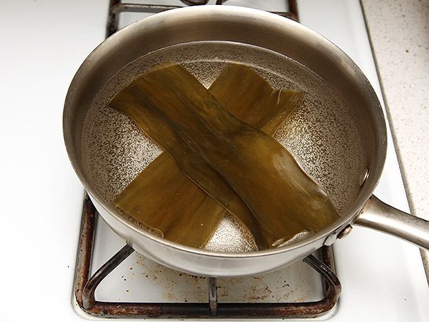 A saucepan filled with water and two large strips of kombu (dried kelp).