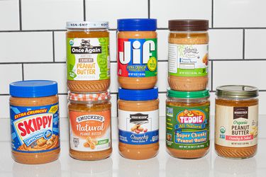 Jars of crunchy peanut butter lined up on a counter.