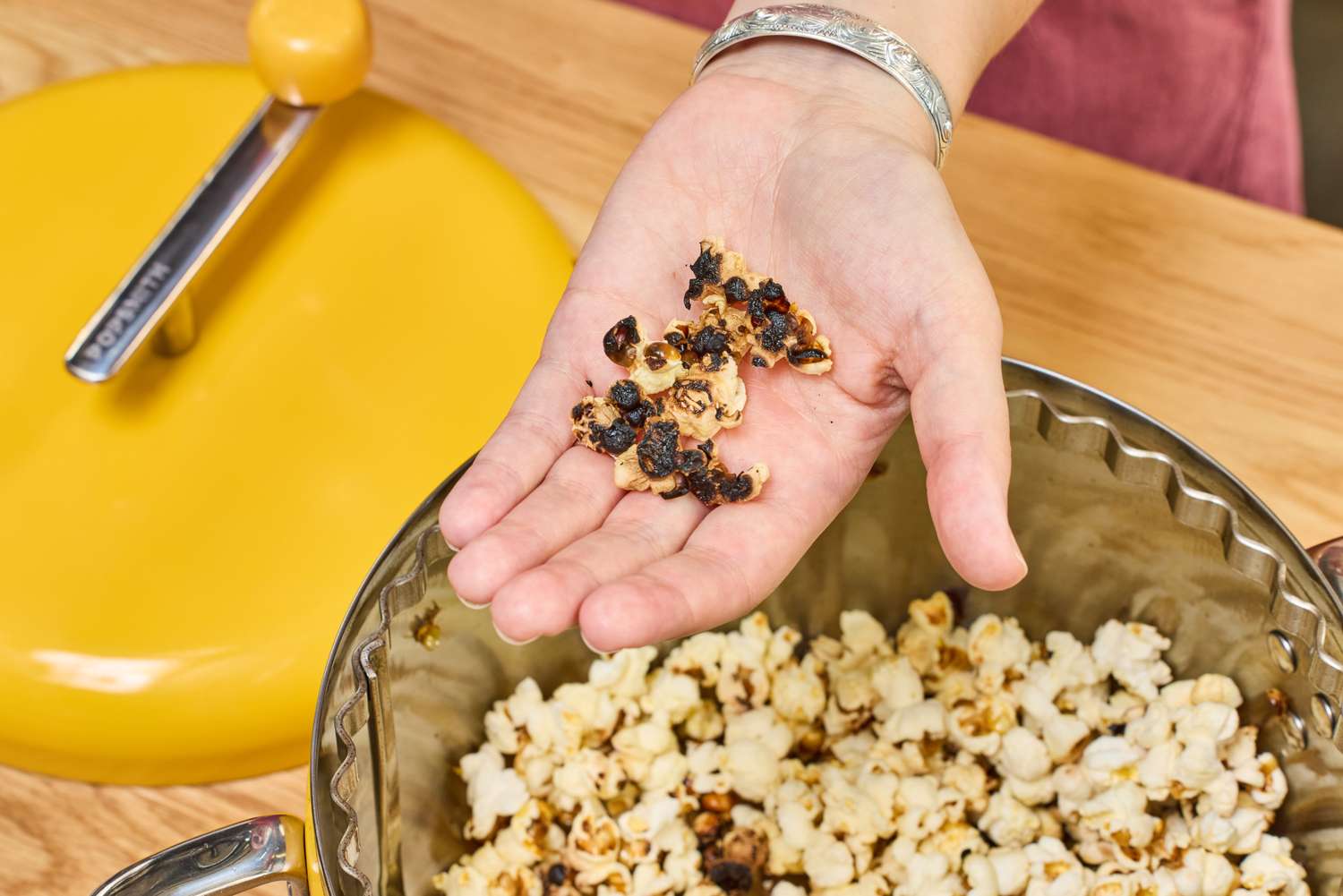 A person holds up burned popcorn after popping in the Popsmith The Popper
