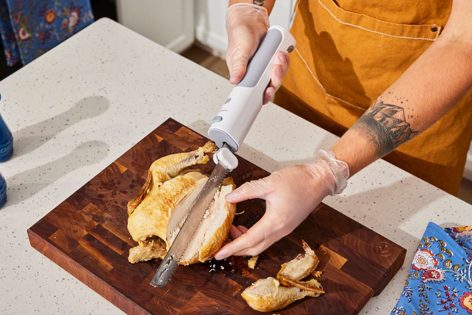 a person using an electric knife to slice a chicken