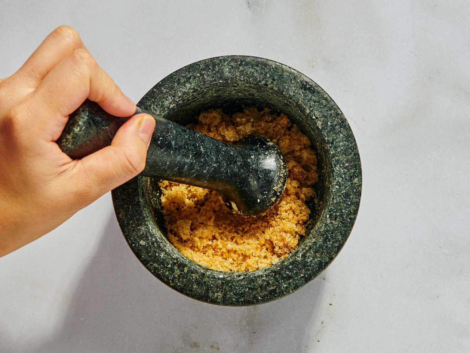 garlic, pork rinds and salt grinding in a mortar and pestle