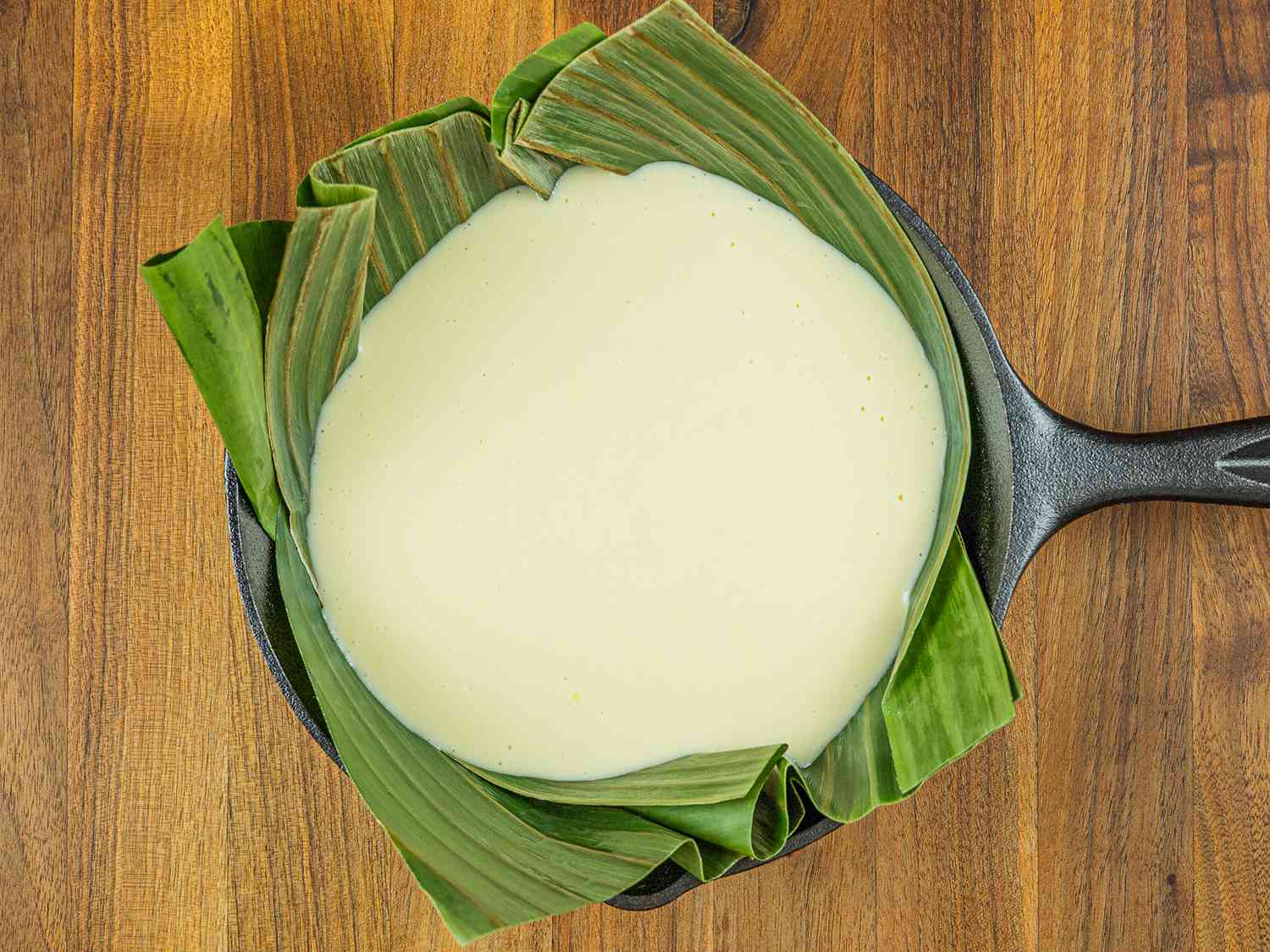 Bibingka batter in banana leaf-lined cast iron pan