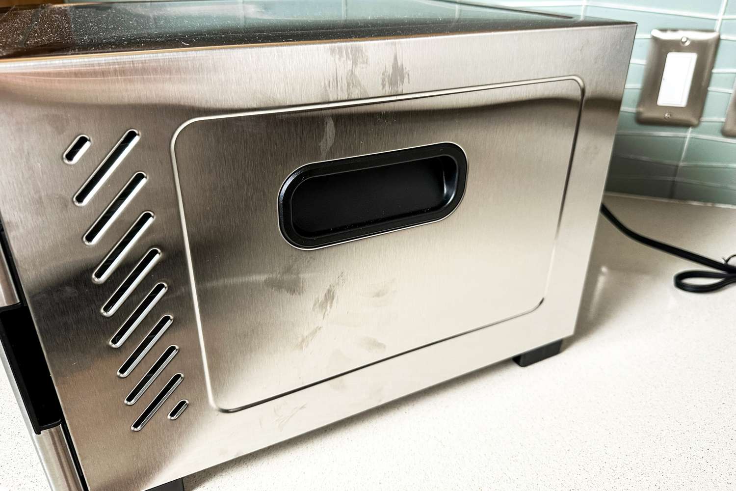 The side of a metal food dehydrator with a focus on the handle