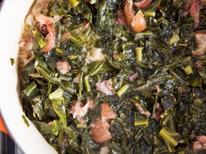 A container of braised collard greens with ham hocks. 